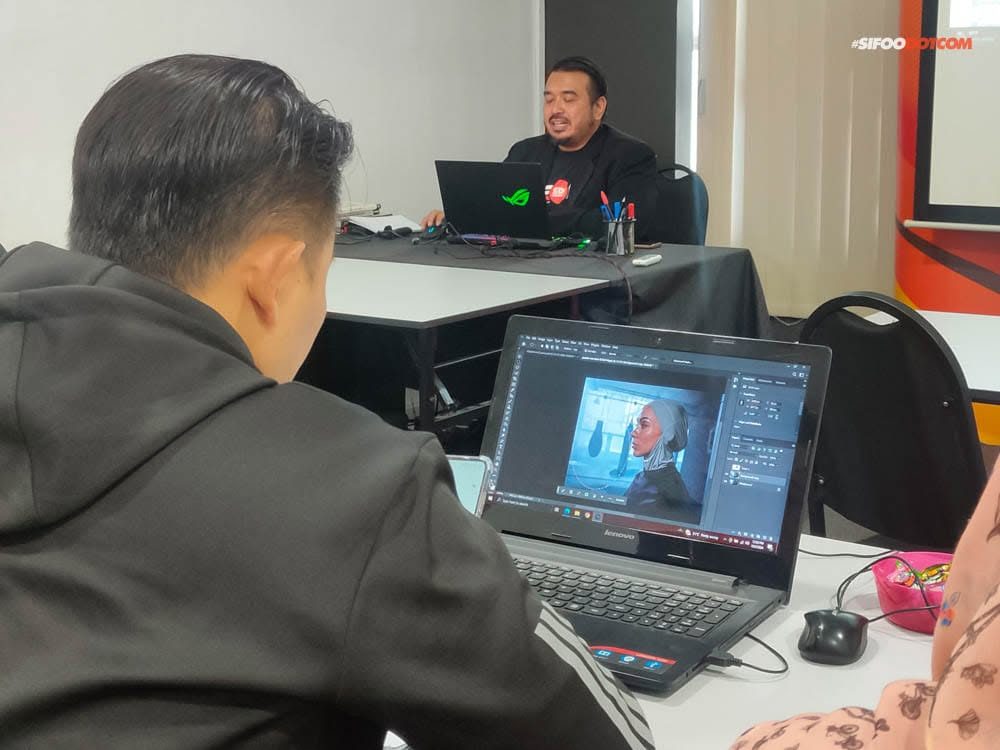Participant editing a portrait in Photoshop while Norzaful speaks from the front