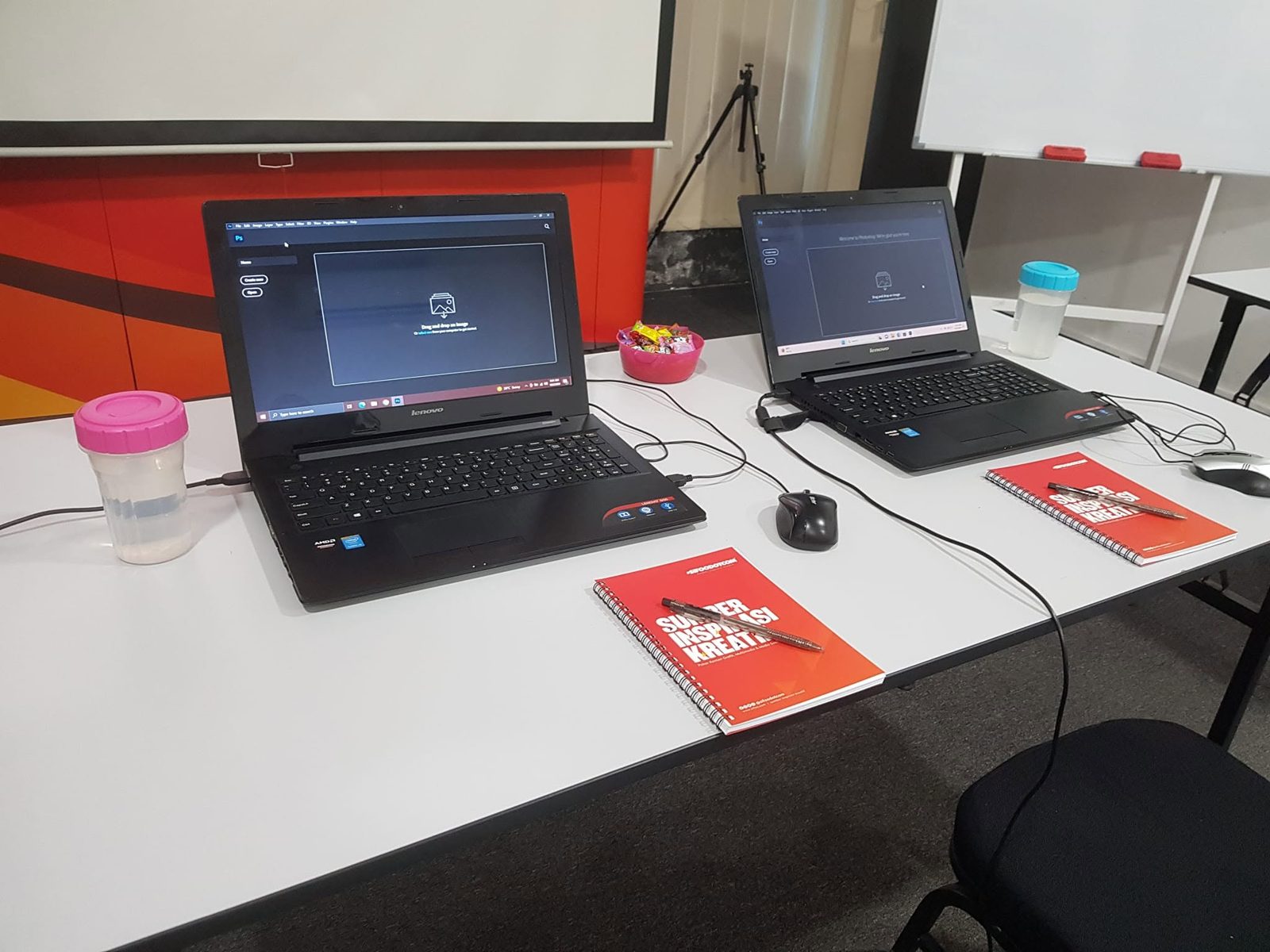 Laptops open on Photoshop with notebooks and pens laid out on a table