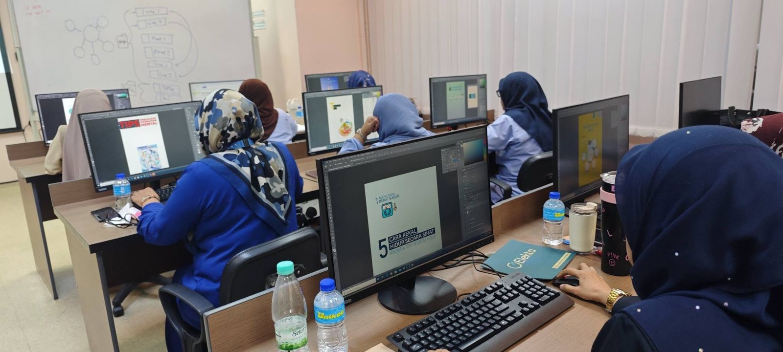 Participants designing health posters in Photoshop at computer stations