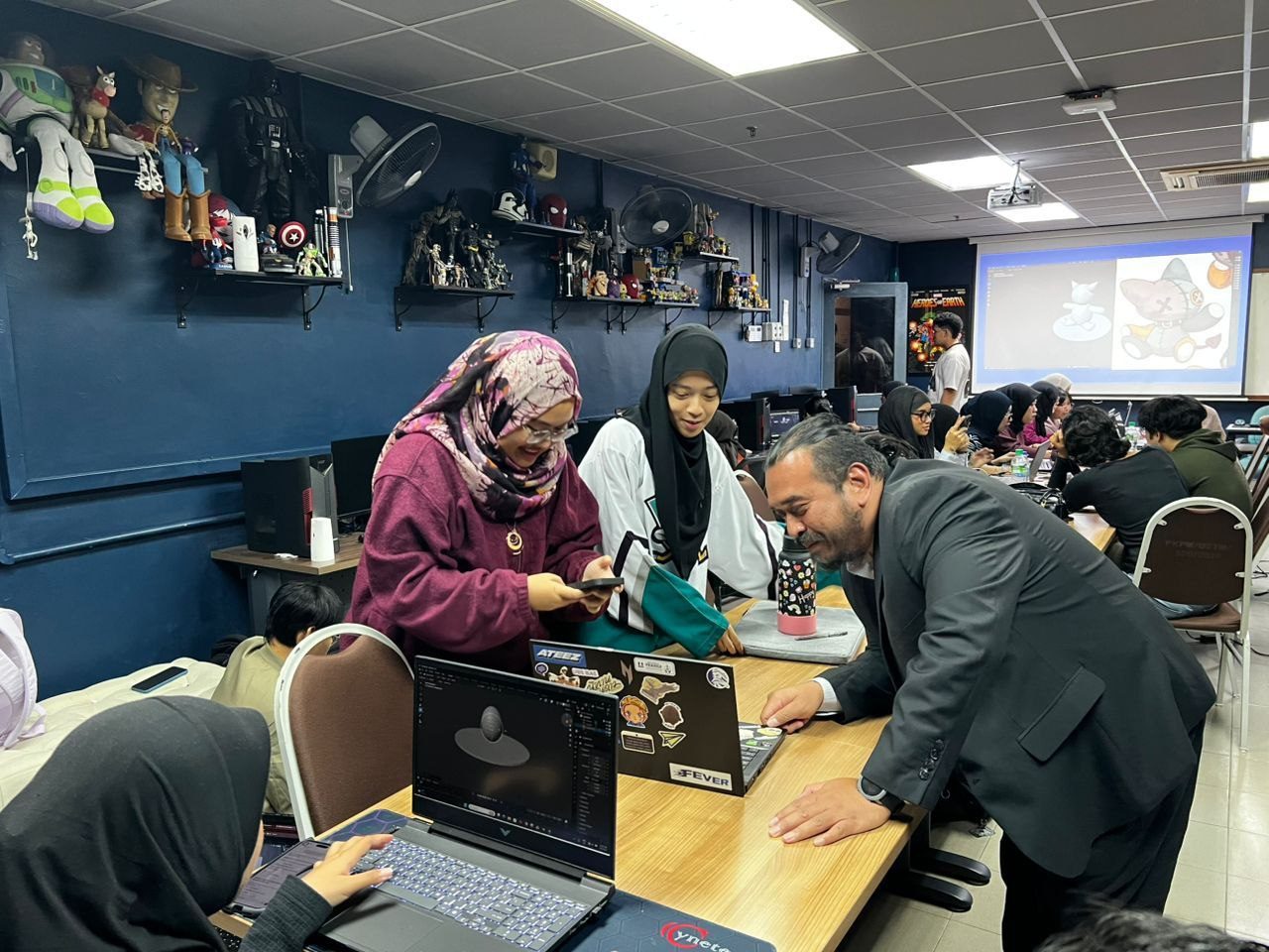 Norzaful reviewing work with two students at a table