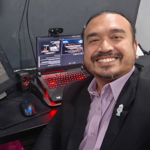 Norzaful smiling at his desk with the title slide on screen