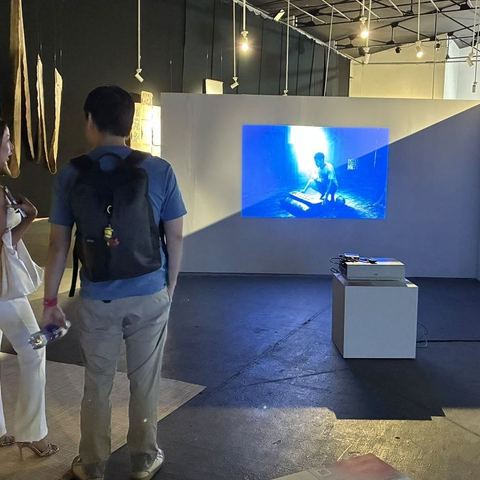 Two visitors watching the projected film in the exhibition space