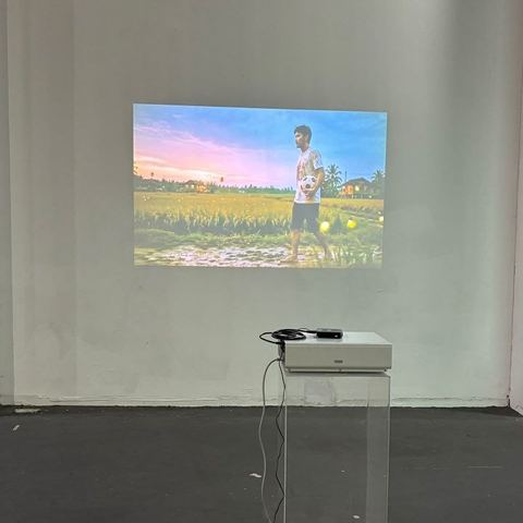 Projected scene of a boy with a football in a paddy field